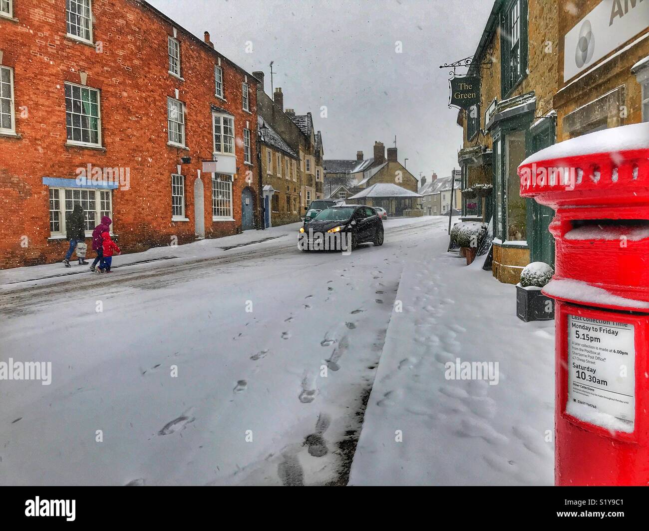 Winter townscape and a red post box with heavy snowfall in Sherborne, Dorset, England during the blizzard of Storm Emma, March 2018 - Smartphone Captured Stock Image