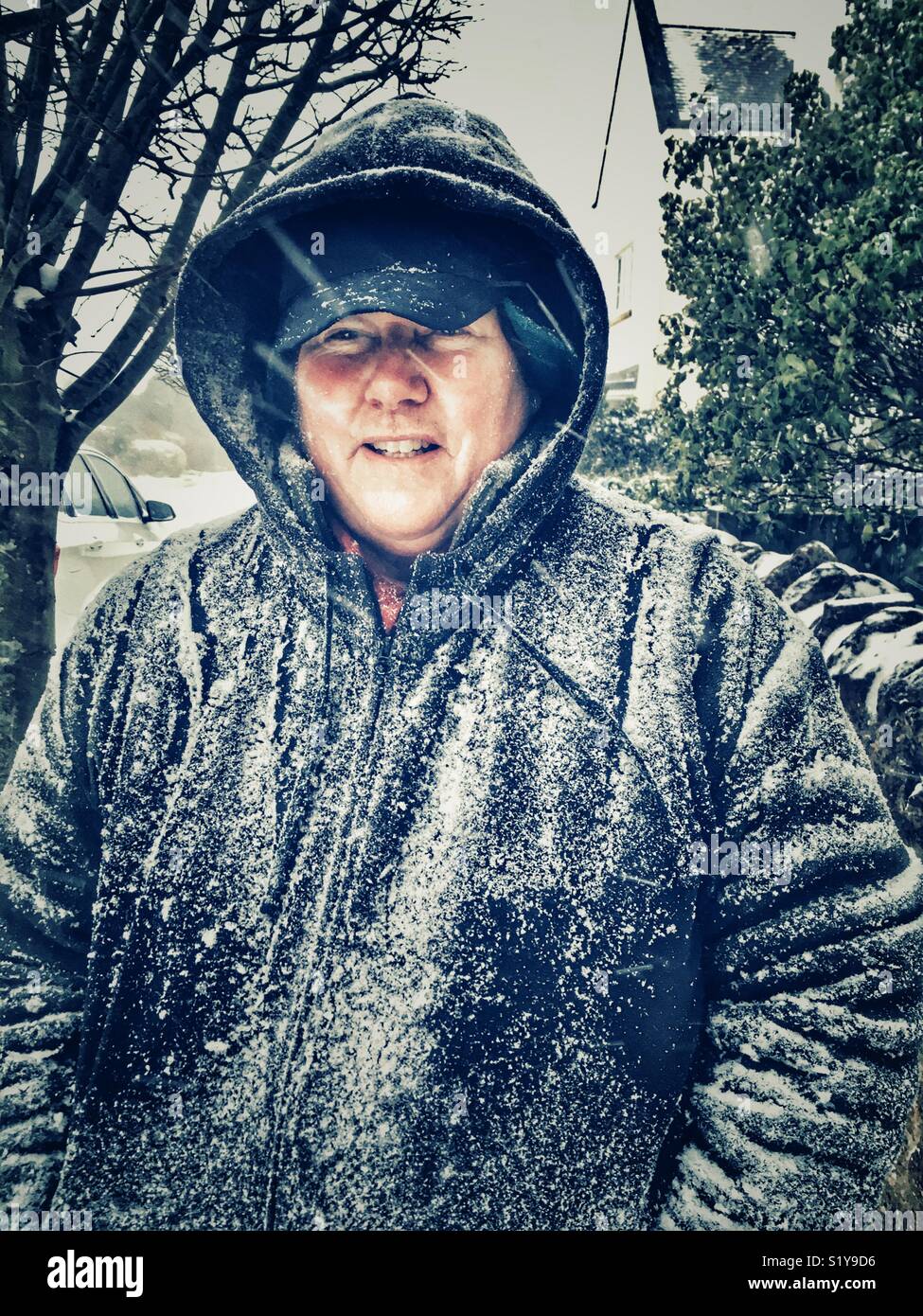 Woman outdoors, in heavy snowfall in Sherborne, Dorset, England during the blizzard of Storm Emma, March 2018 - Smartphone Captured Stock Image