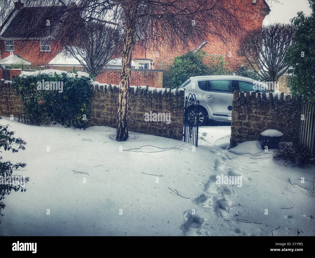 View from front door to parked car with footsteps in deep snow. Dorset, England. Stock Photo