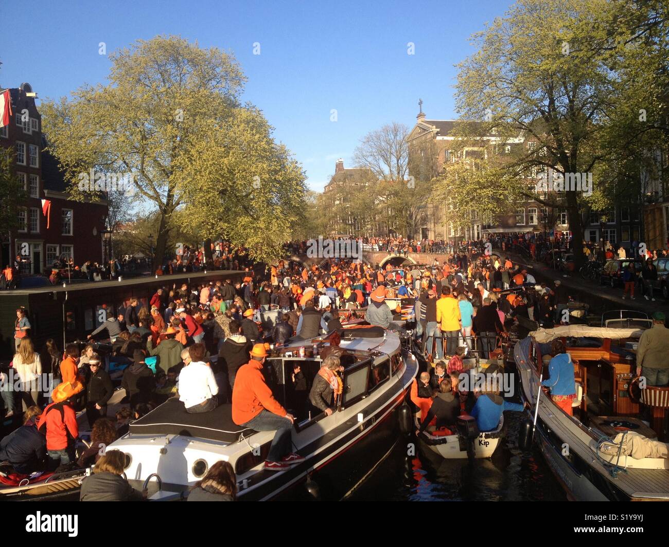 Amsterdam during Koningsdag, a Dutch national holiday. On the canals there are many small boats with people partying on them. Stock Photo