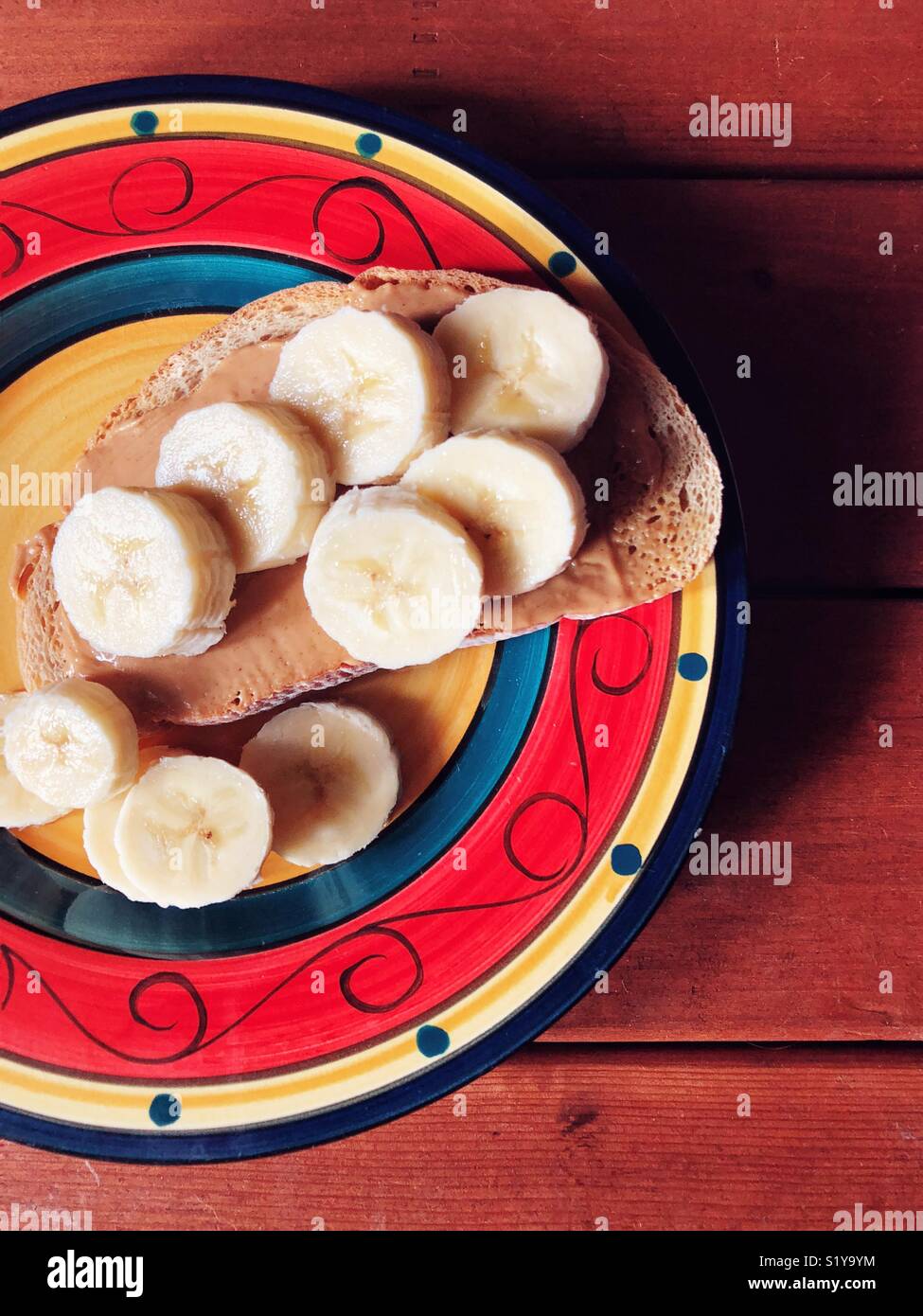 Colourful plate with banana slices and peanut butter on rye toast - Smartphone Captured Stock Image