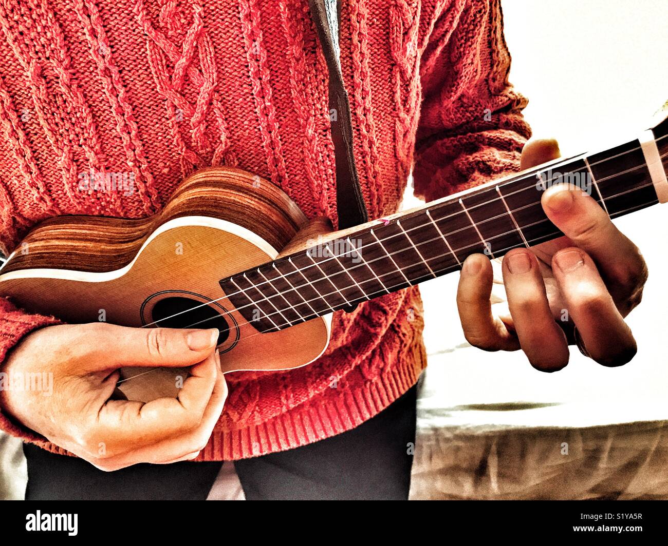 Woman playing soprano ukulele, indoors - Smartphone Captured Stock Image
