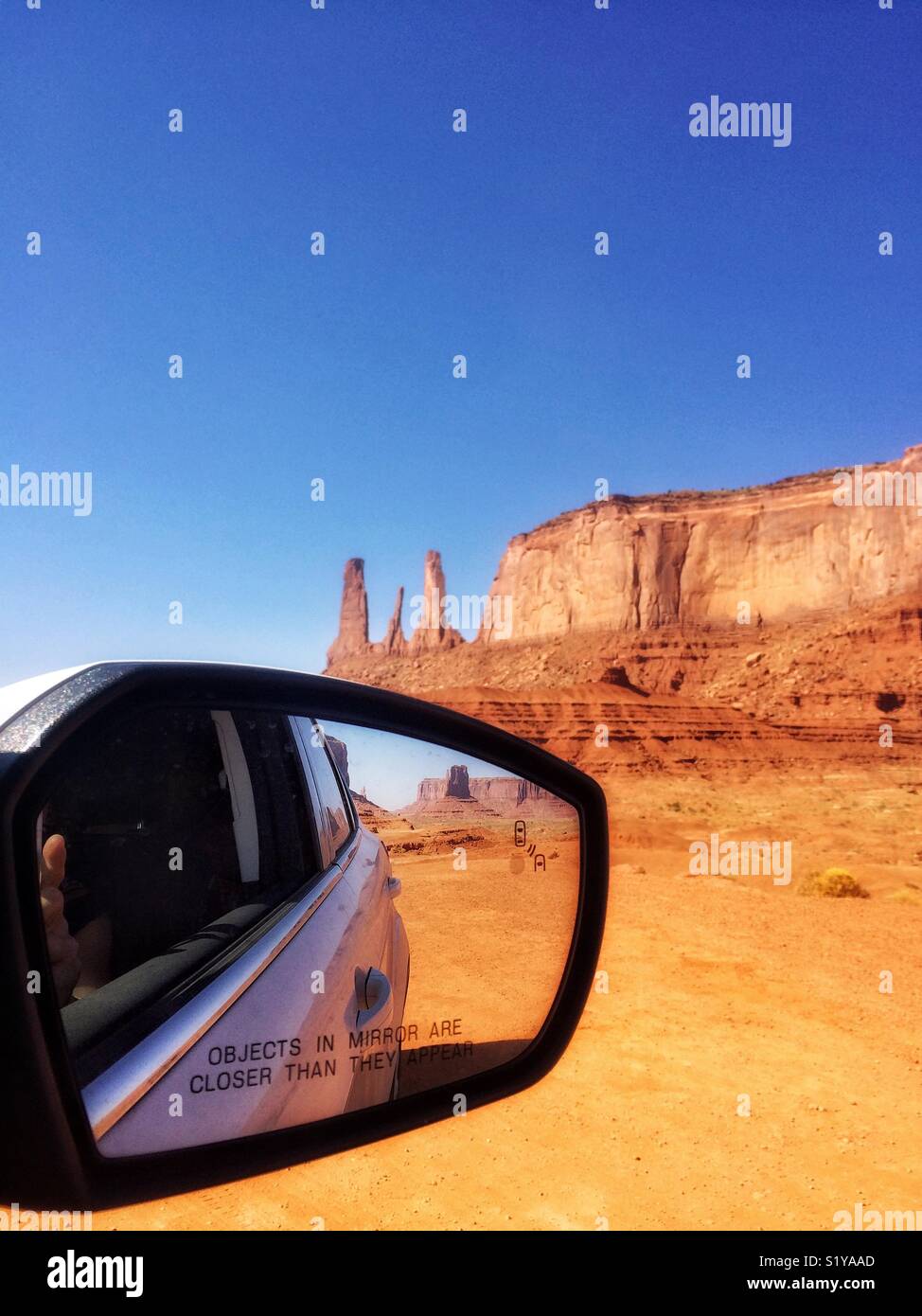 Three sisters at Monument Valley landscape and rearview mirror of a car, Navajo Tribal Park on the border of Utah and Arizona, USA - Smartphone Captured Stock Image