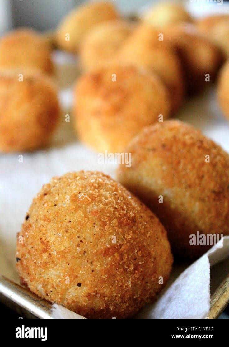 Golden brown arancini risotto balls sit on a bed of paper towels after frying in oil. - Smartphone Captured Stock Image