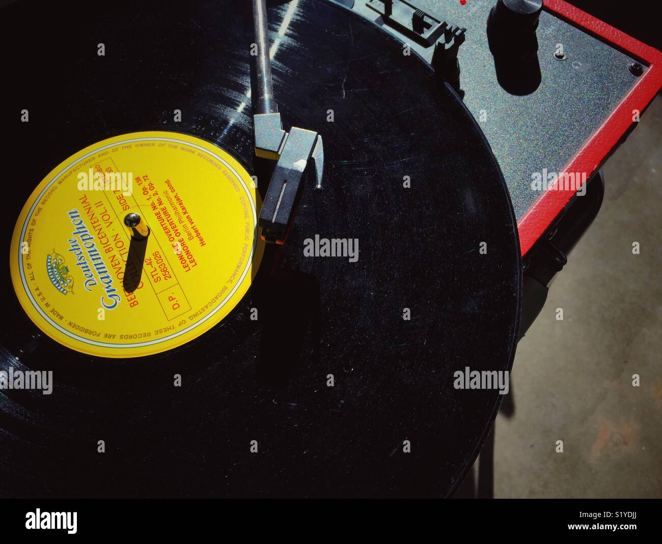 Bright sunlight shines on vintage record player with dusty record Stock