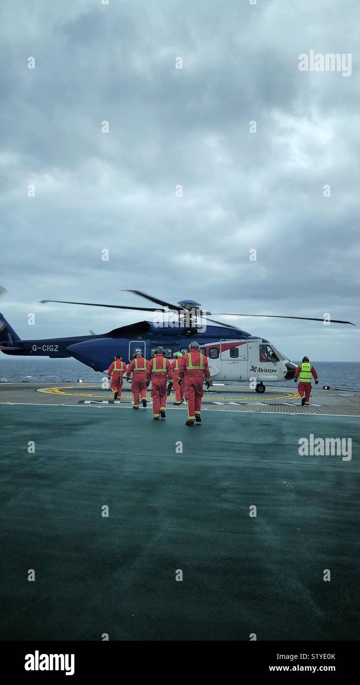 Helideck crew attending landed Sikorsky S92 helicopter landed on North Sea FPSO - credit Lee Ramsden / Alamy Stock Photo