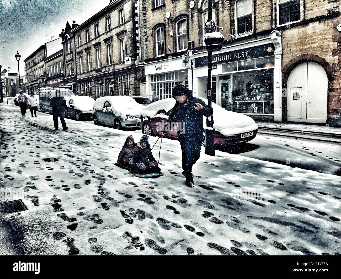 UK, Weather, Sherborne, Dorset. Father pulling children on a toboggan down Cheap Street in Sherborne as the so called mini Beast from the East brings another icy blast to the South West. - Smartphone Captured Stock Image