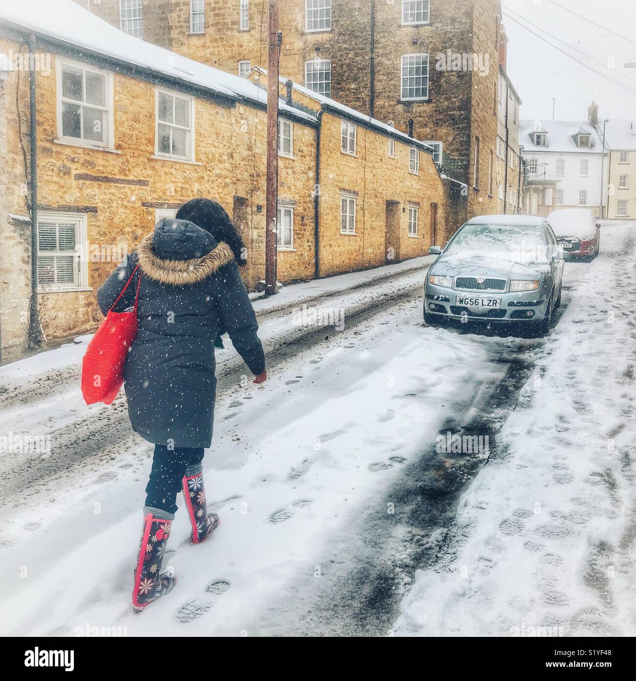 UK, Weather, Sherborne, Dorset. Woman walking in Upper Cheap Street through the snow as the so called mini Beast from the East brings another icy blast to the South West. - Smartphone Captured Stock Image