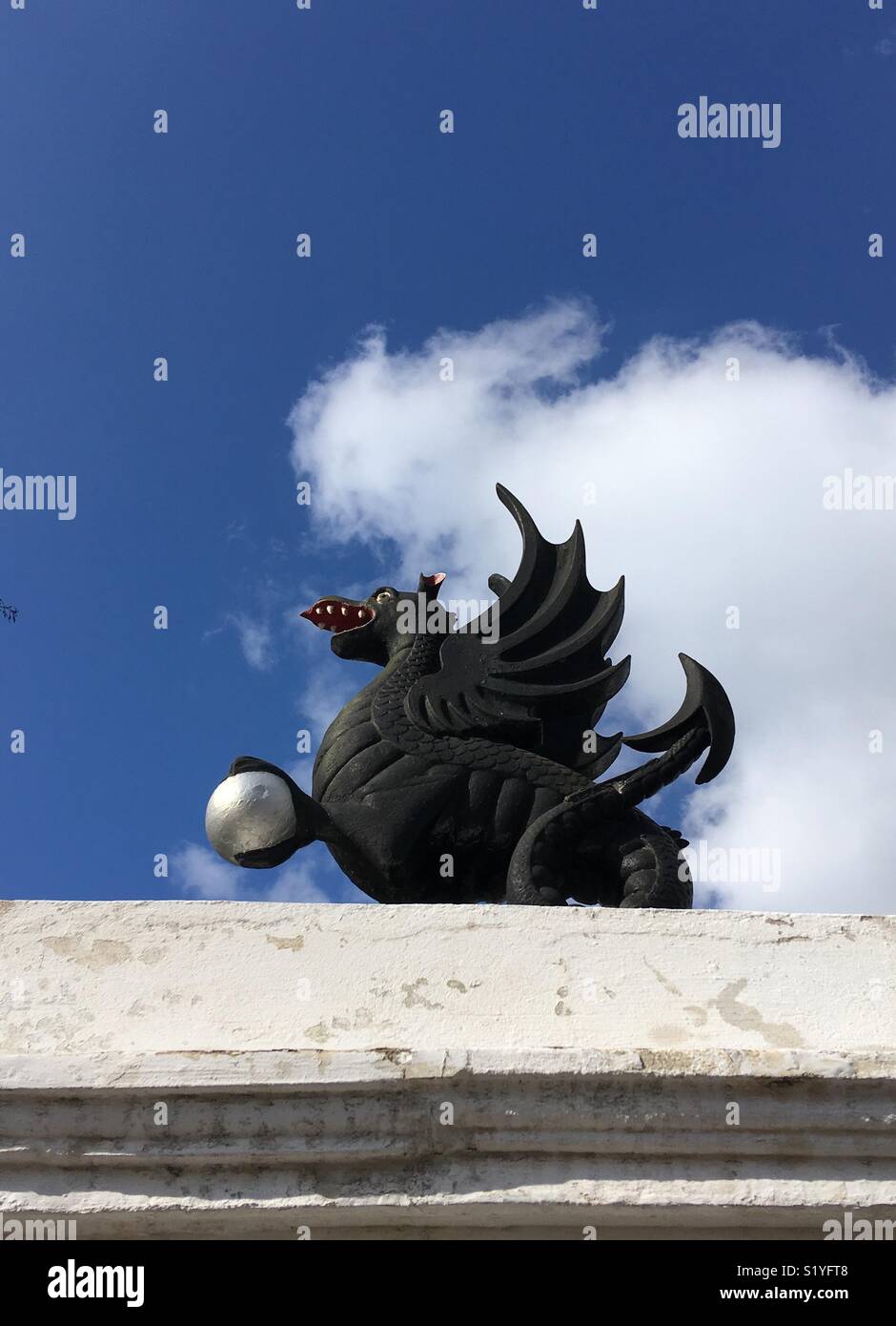 Statue of a dragon clutching a silver ball. Stock Photo