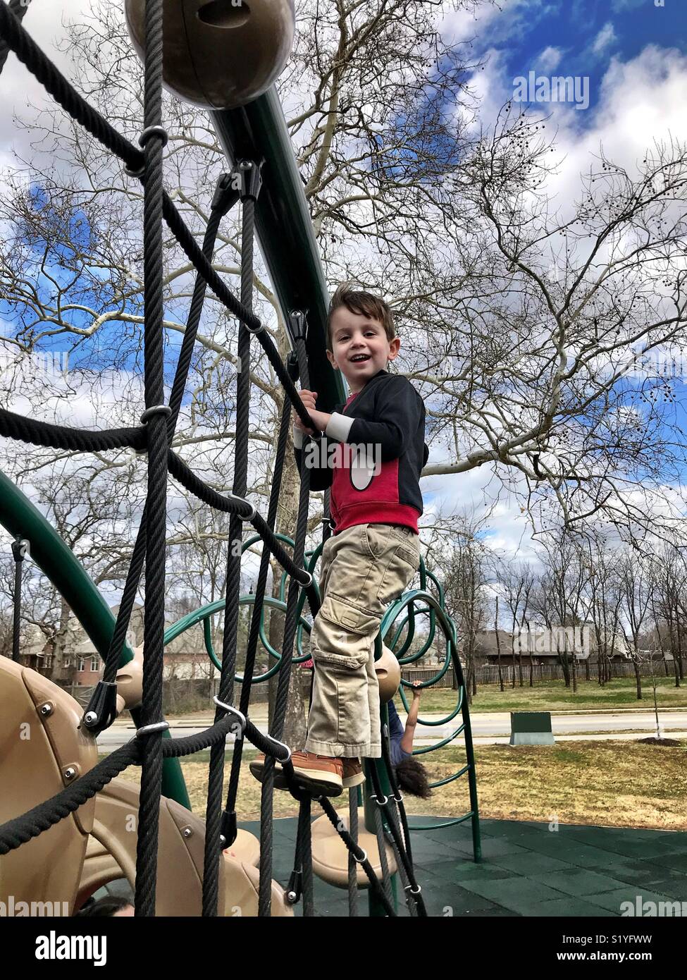 A little boy climbs a rope wall at a playground in Bentonville