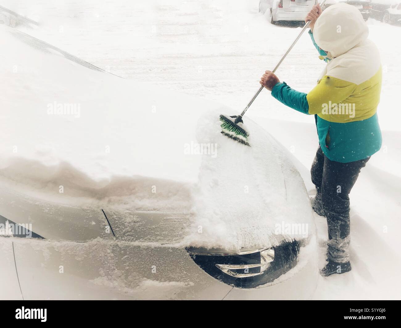 Man cleaning snow from his car - Smartphone Captured Stock Image