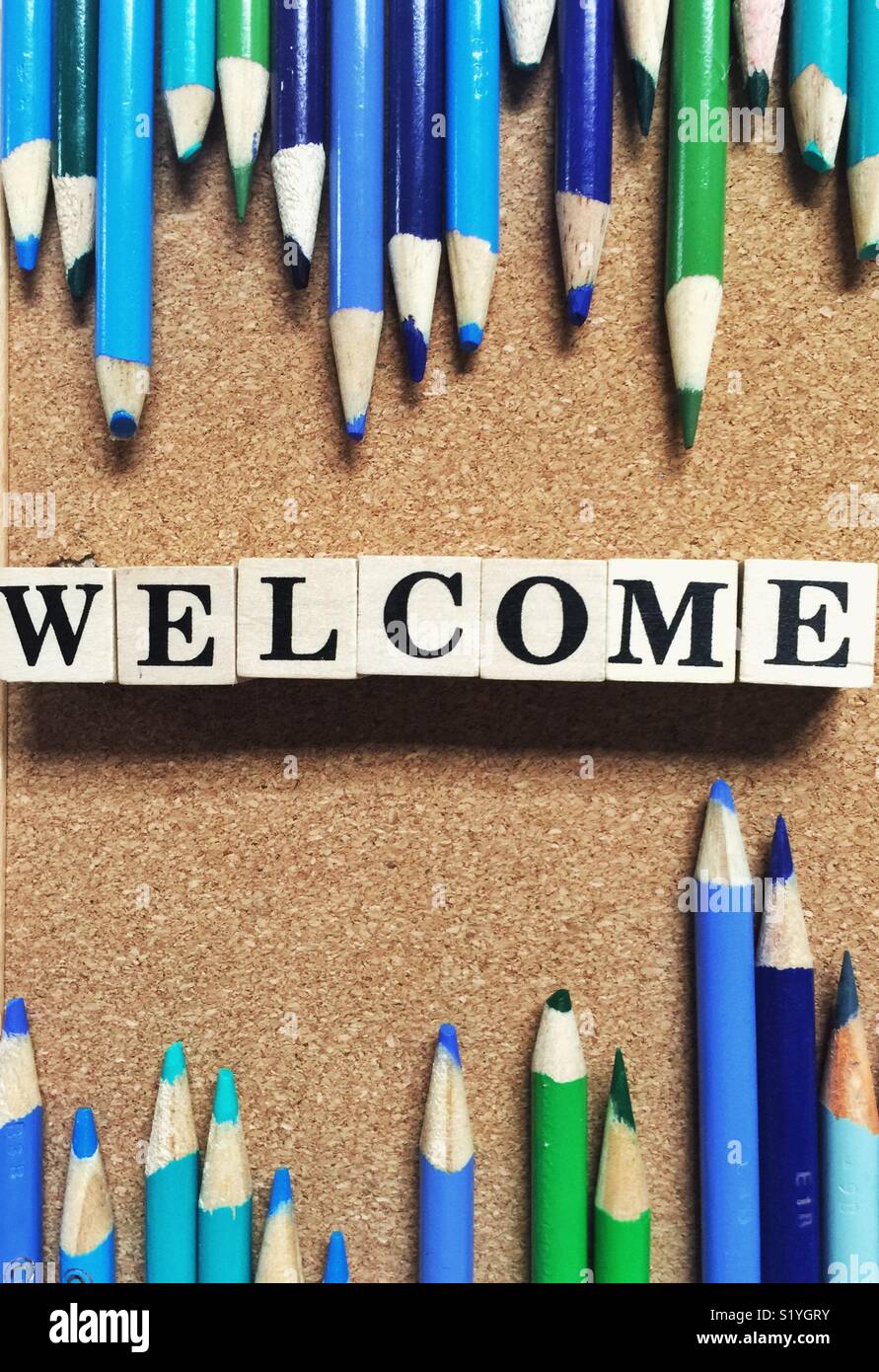 Welcome sign crafted on cork board with colored pencils and wooden blocks Stock Photo