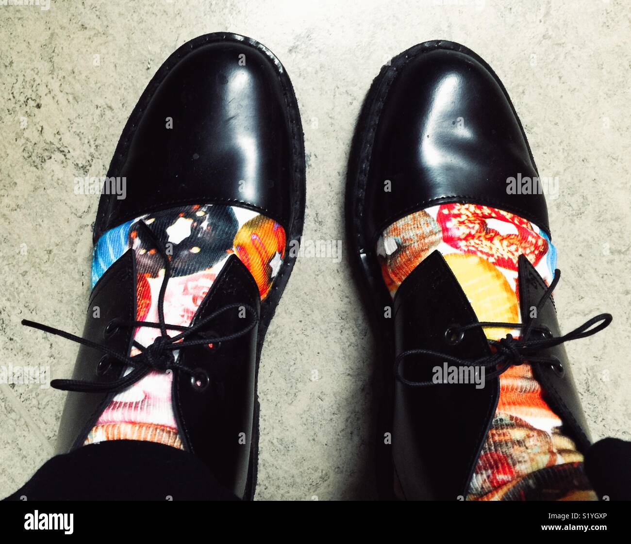 feet in Socks with doughnuts and fancy black shoes Stock Photo