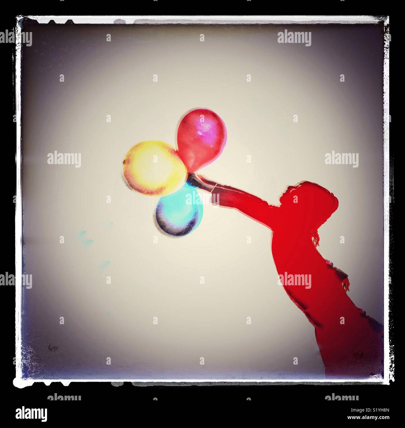 A child clutching a bunch of colourful balloons. - Smartphone Captured Stock Image