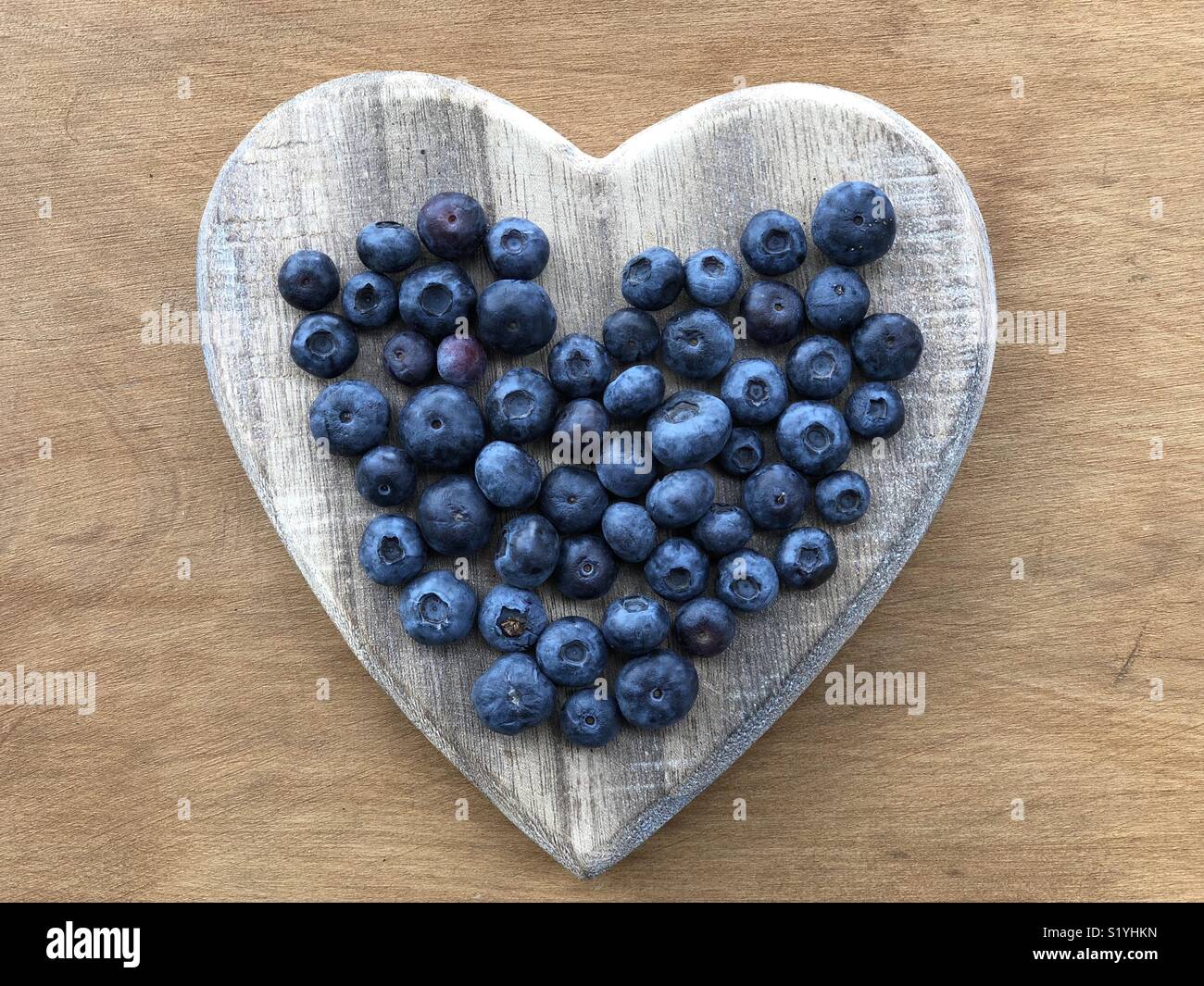 Close-up view of fresh Blueberries on a wooden heart - Smartphone Captured Stock Image