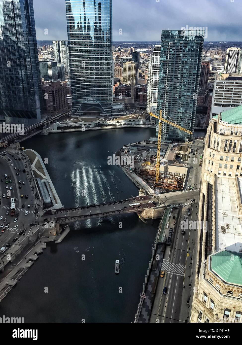 Reflections of light paint lines on the Chicago River as seen from above, while a boat travels by and morning commuter traffic runs alongside it. Stock Photo