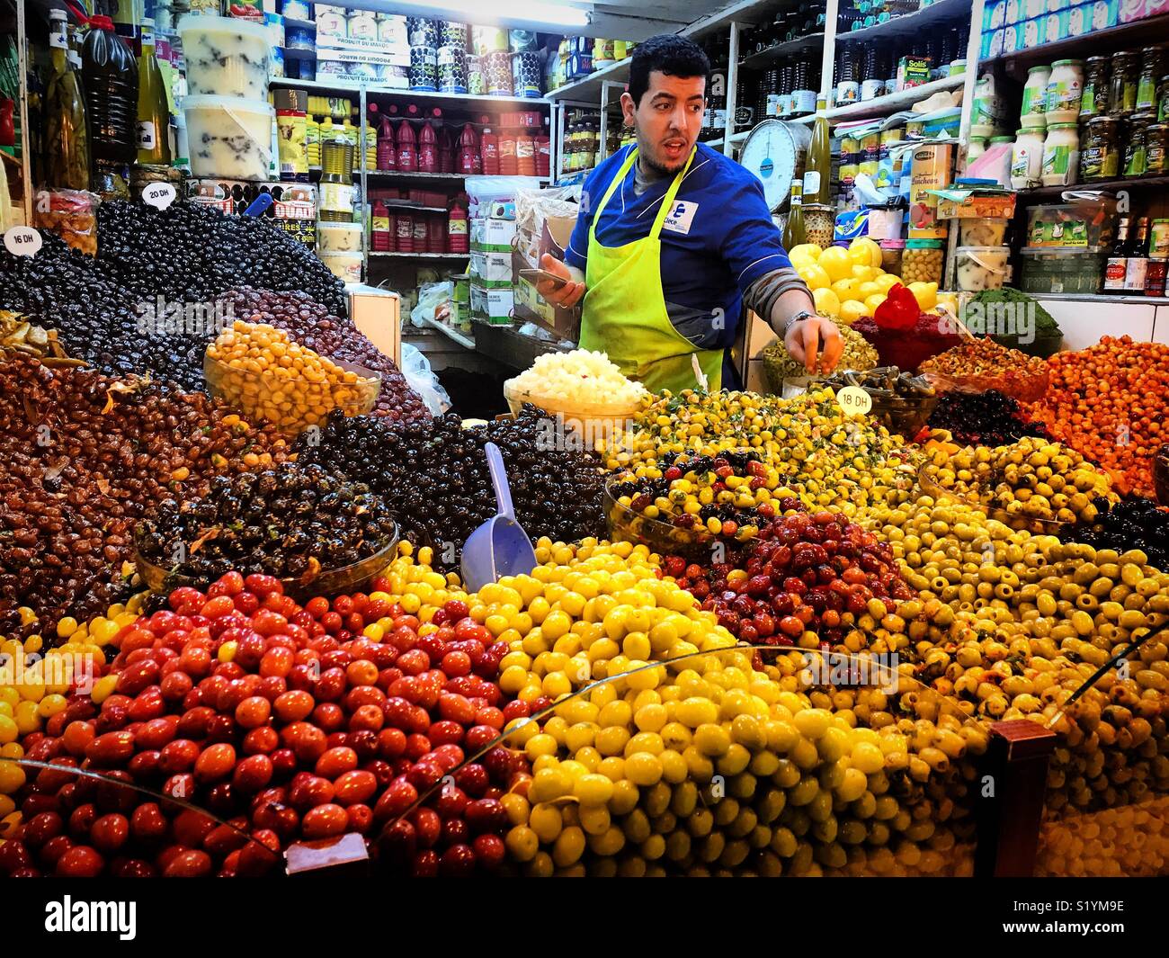 A man sells olives in a market in Tangier, Morroco, Africa - Smartphone Captured Stock Image