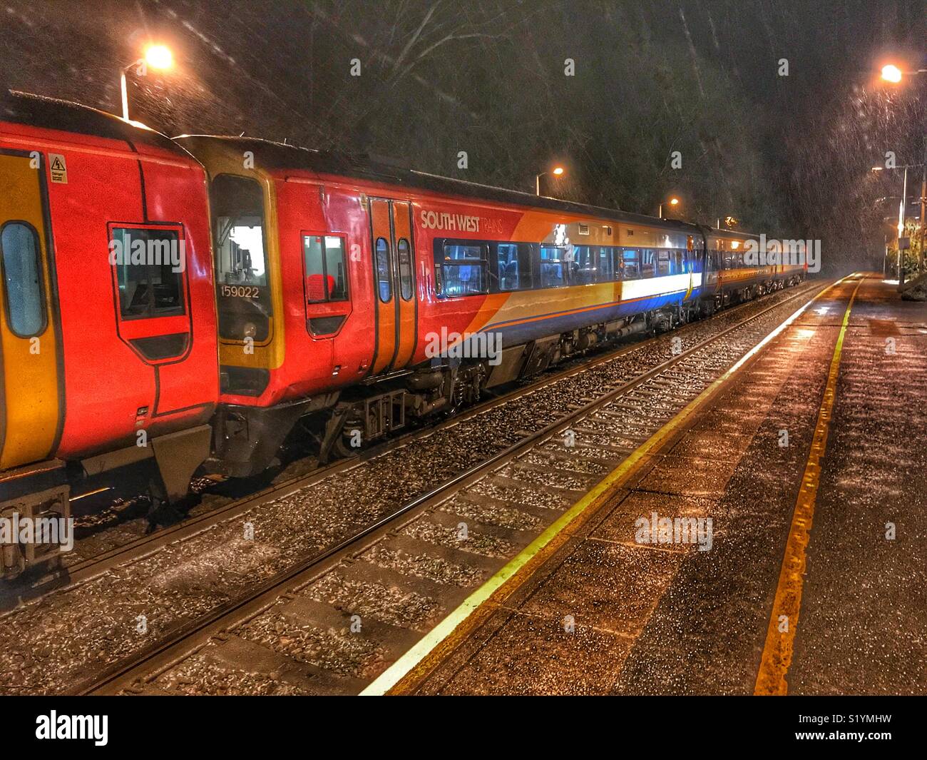 South West Train at Sherborne Station at dawn, empty train, salt grit on the platform, and snow falling, Dorset, England - Smartphone Captured Stock Image