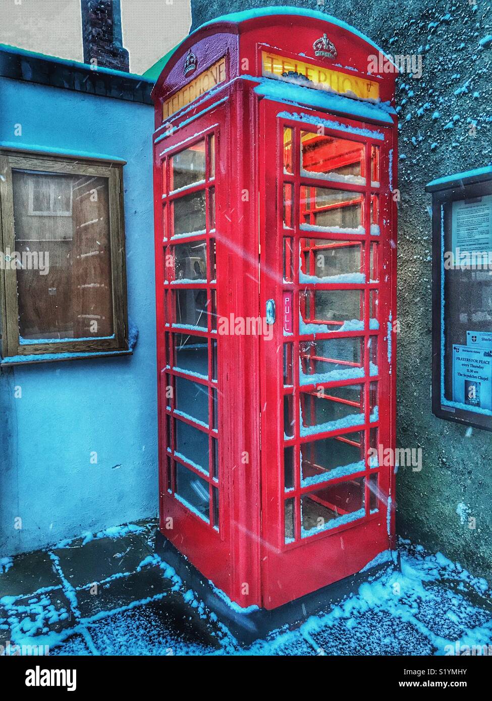 Phone booth in Cheap Street at dawn, with snow on the ground and a blizzard just starting, Beast from the East, Sherborne, Dorset, England, March 2018 - Smartphone Captured Stock Image