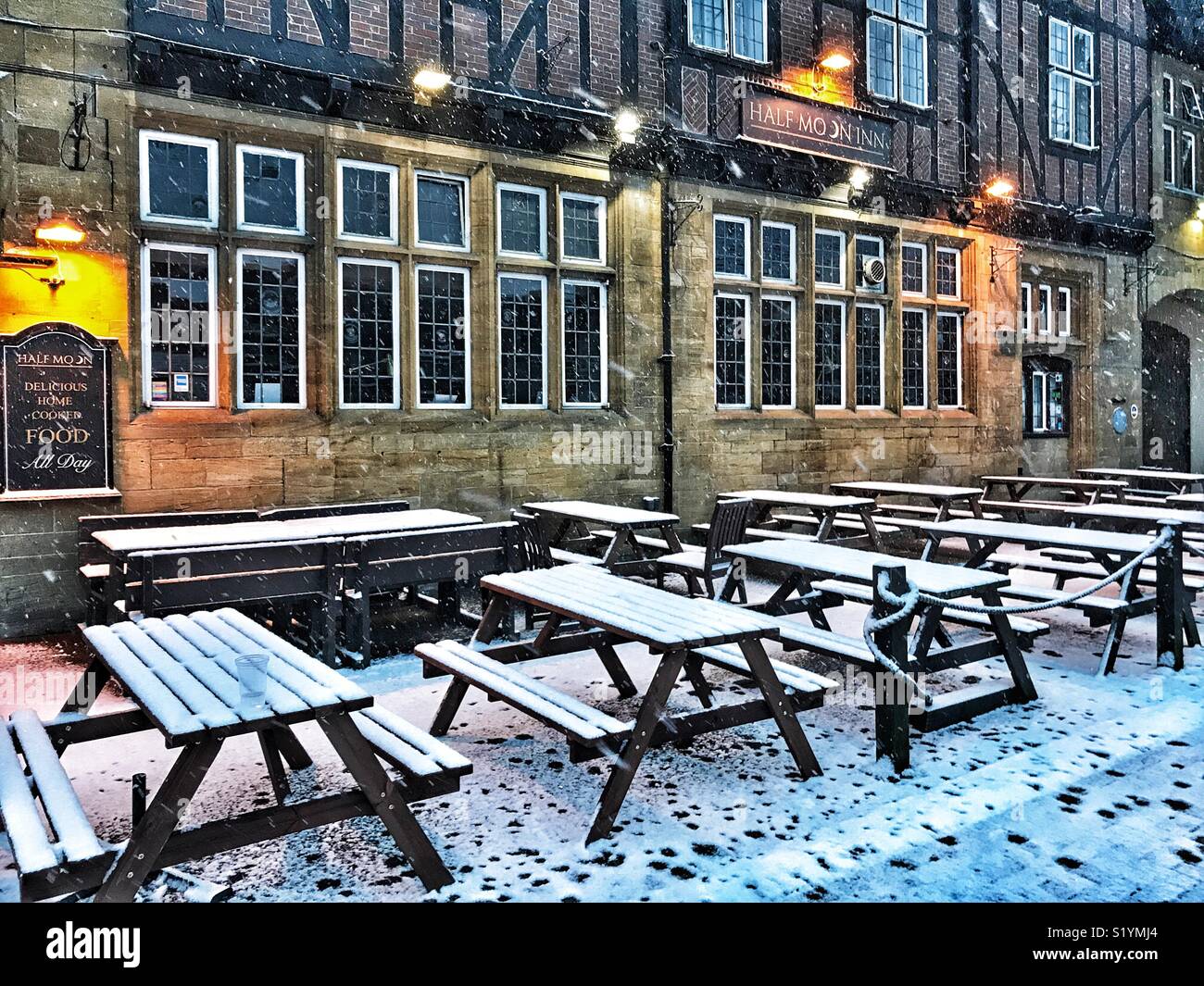 Half Moon Inn, outdoor seating area, dawn, with snow on the ground and a blizzard just starting, Beast from the East, Sherborne, Dorset, England, March 2018 - Smartphone Captured Stock Image