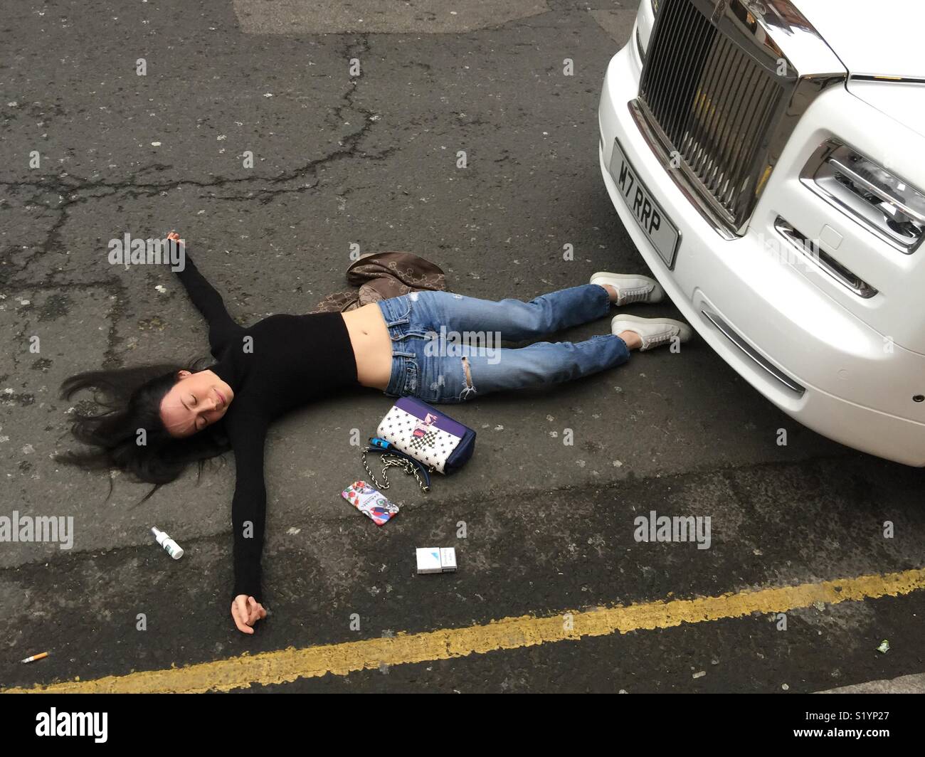 Young woman laying in the road acting. - Smartphone Captured Stock Image