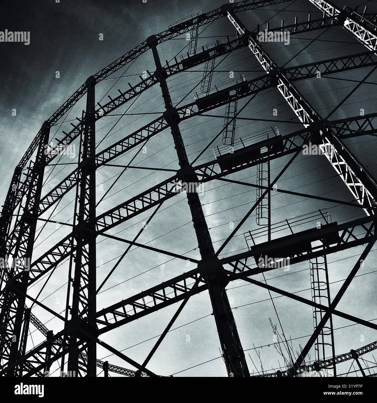 Metal skeleton of empty gasometer in silhouette against sky - Smartphone Captured Stock Image