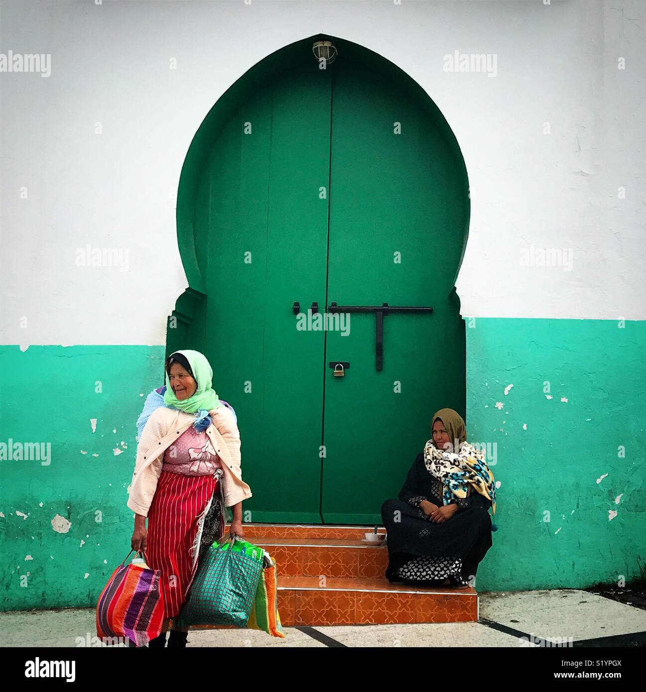 Morrocan women sit in front of a green door in Tangier, Morroco, Africa Stock Photo