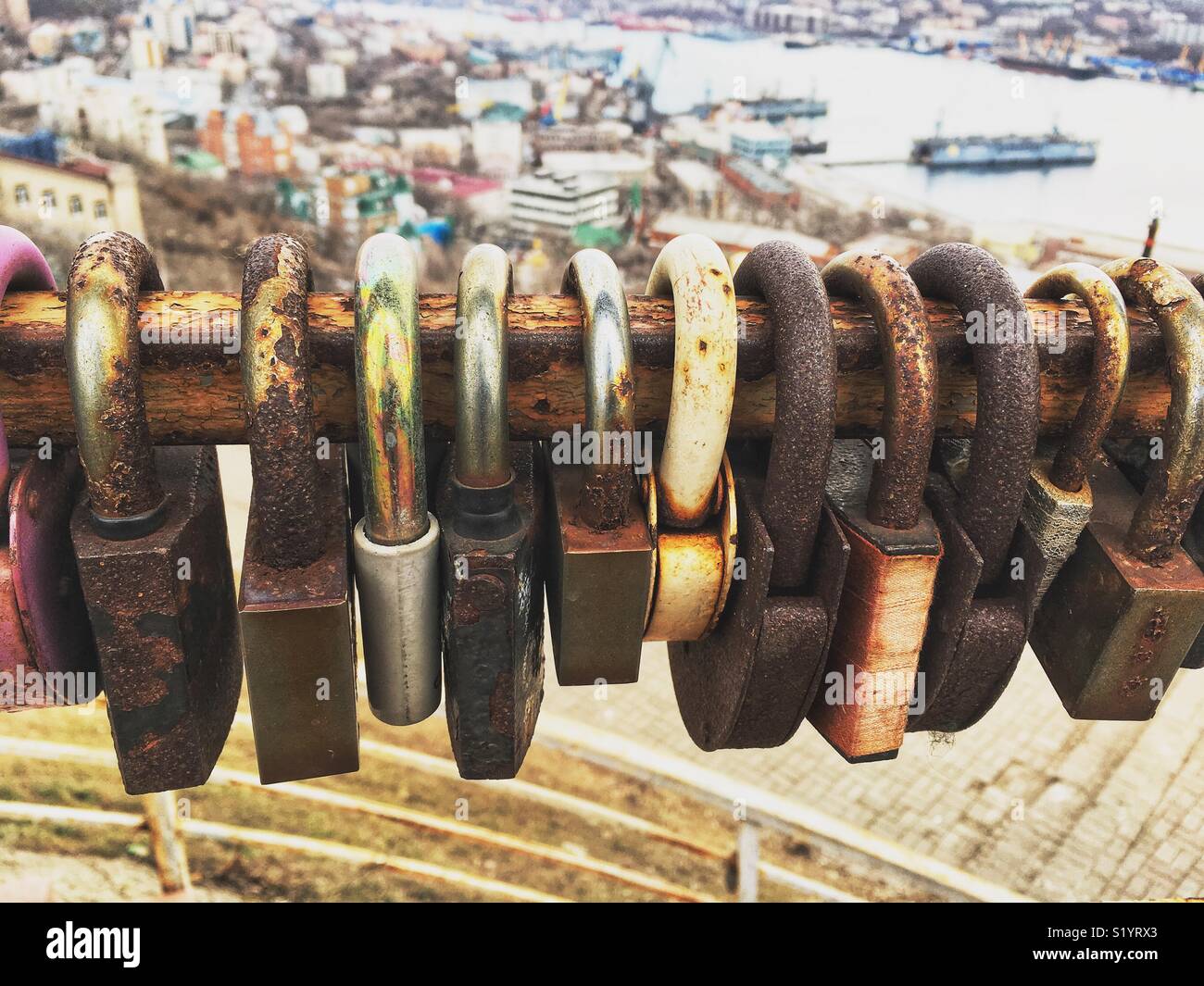 Row of rusty love locks on a rail and port overview on the background - Smartphone Captured Stock Image