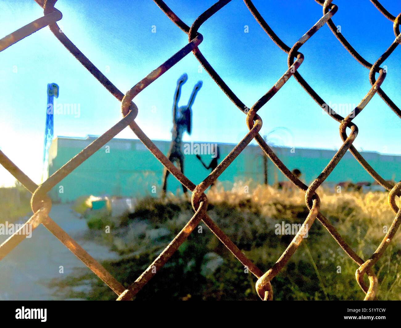 Chainlink fence outside a field of worshippers made of steel. - Smartphone Captured Stock Image