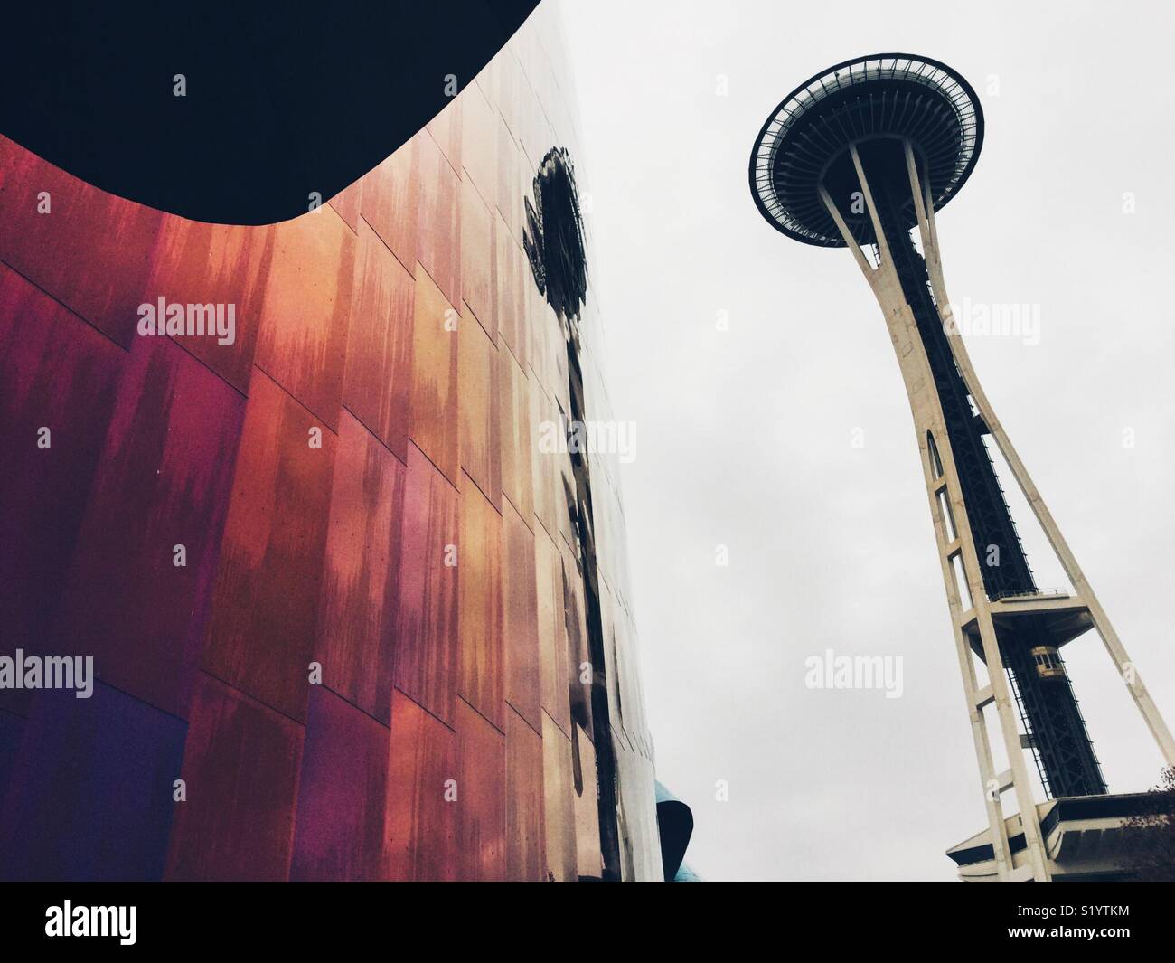 Iconic Space Needle in Seattle  reflecting in purple wall of MoPop museum designed by Frank Gehry - Smartphone Captured Stock Image