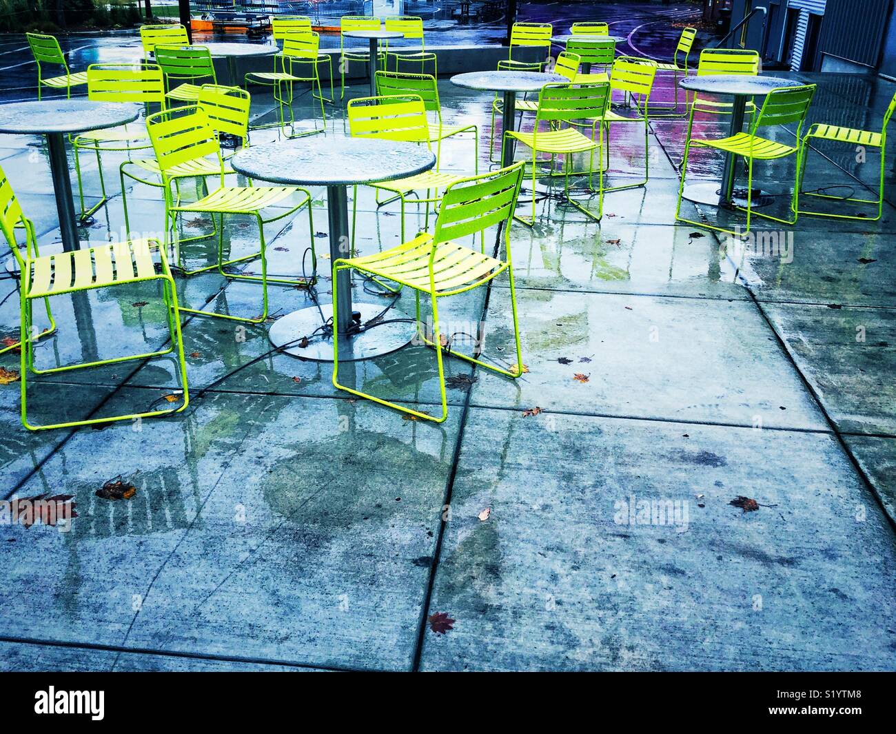 Green chairs and metal tables in the rain in outdoor cafe in Seattle - Smartphone Captured Stock Image