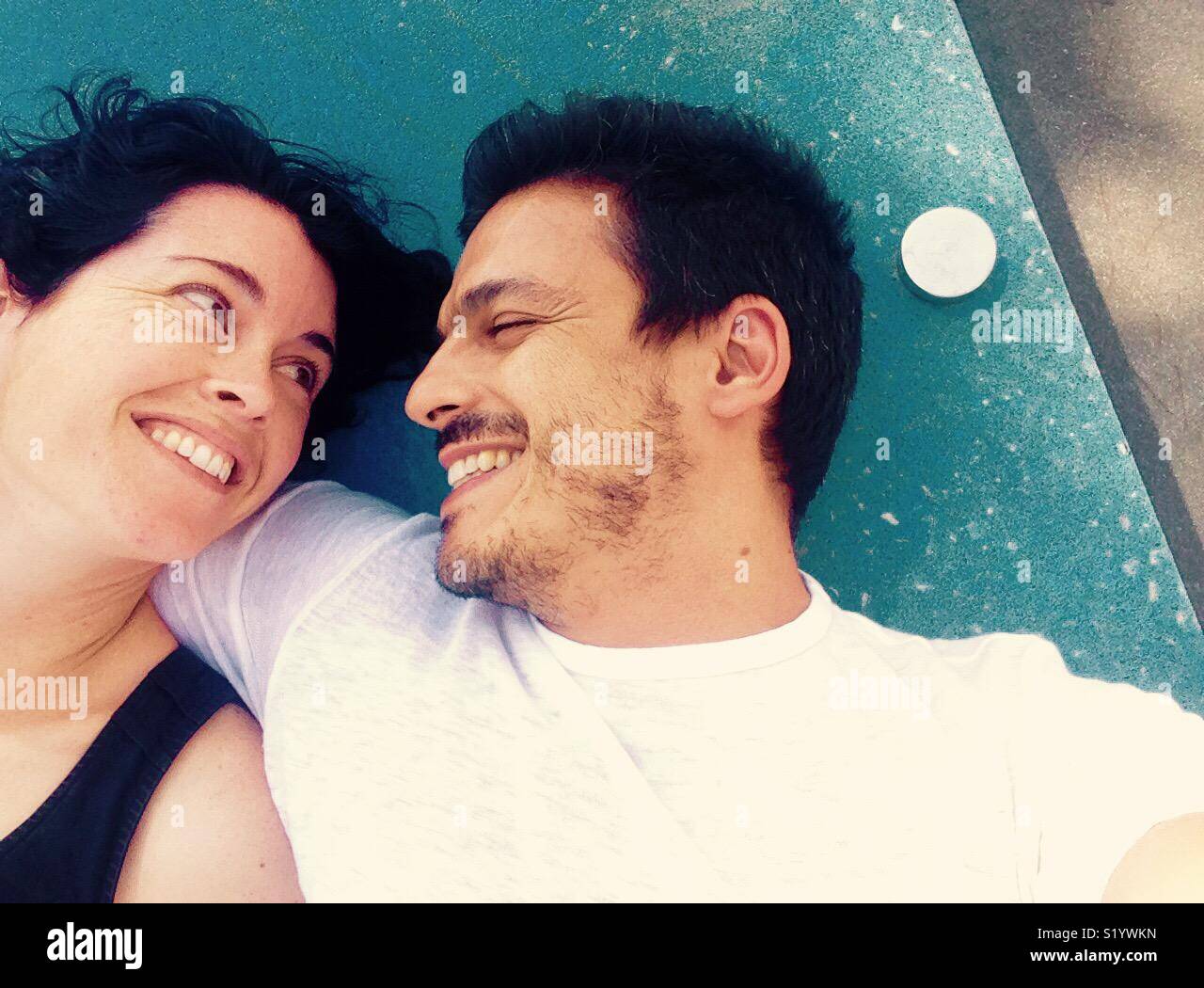 Lovers smiling at each other lying down outside - Smartphone Captured Stock Image