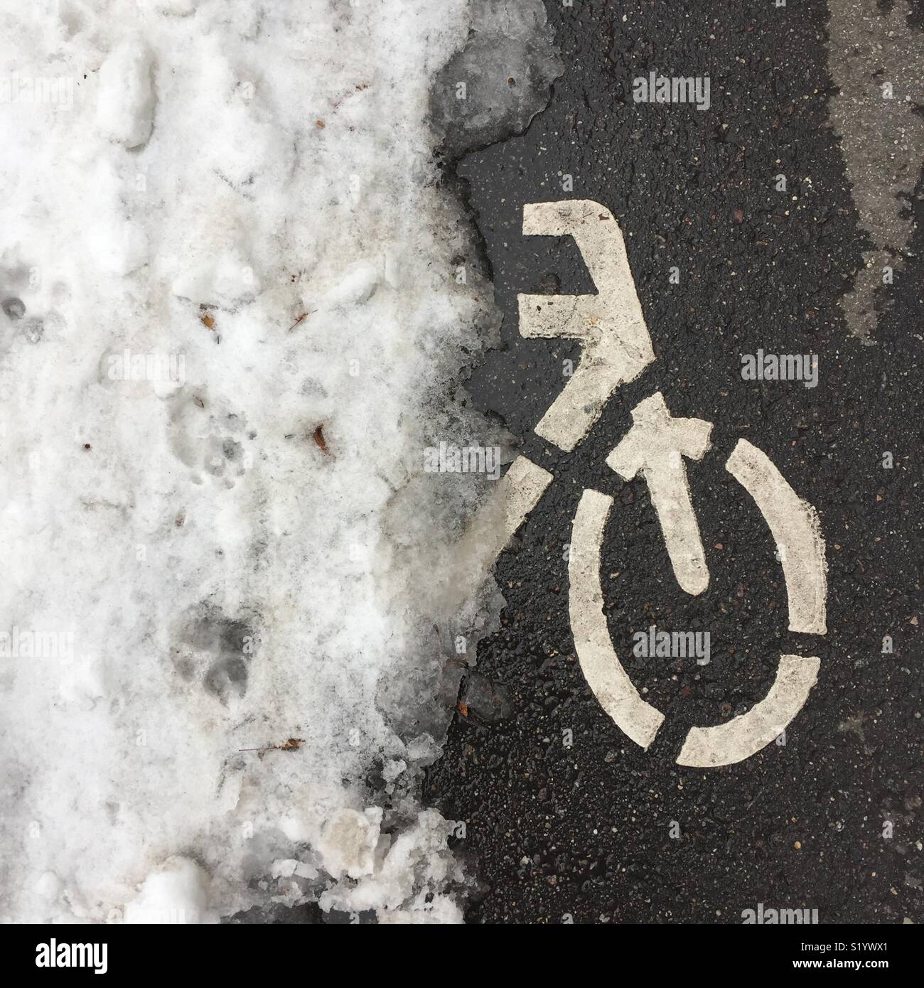 Bicycle template on the asphalt road under layer of snow. Spring time in the city. - Smartphone Captured Stock Image