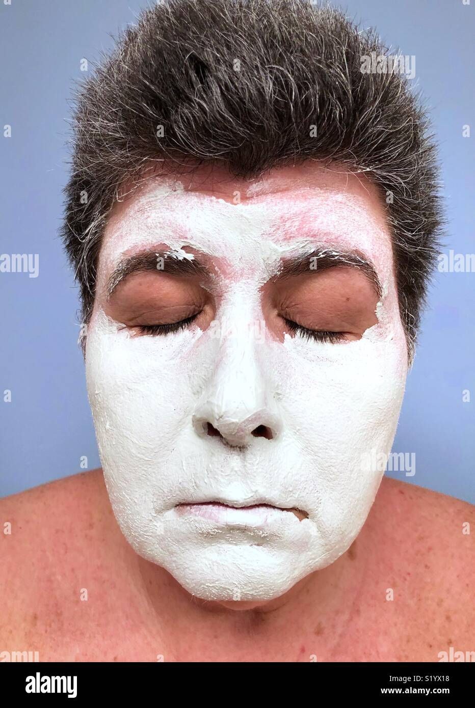 A Caucasian Woman With Dark Hair Wearing A White Clay Face Mask