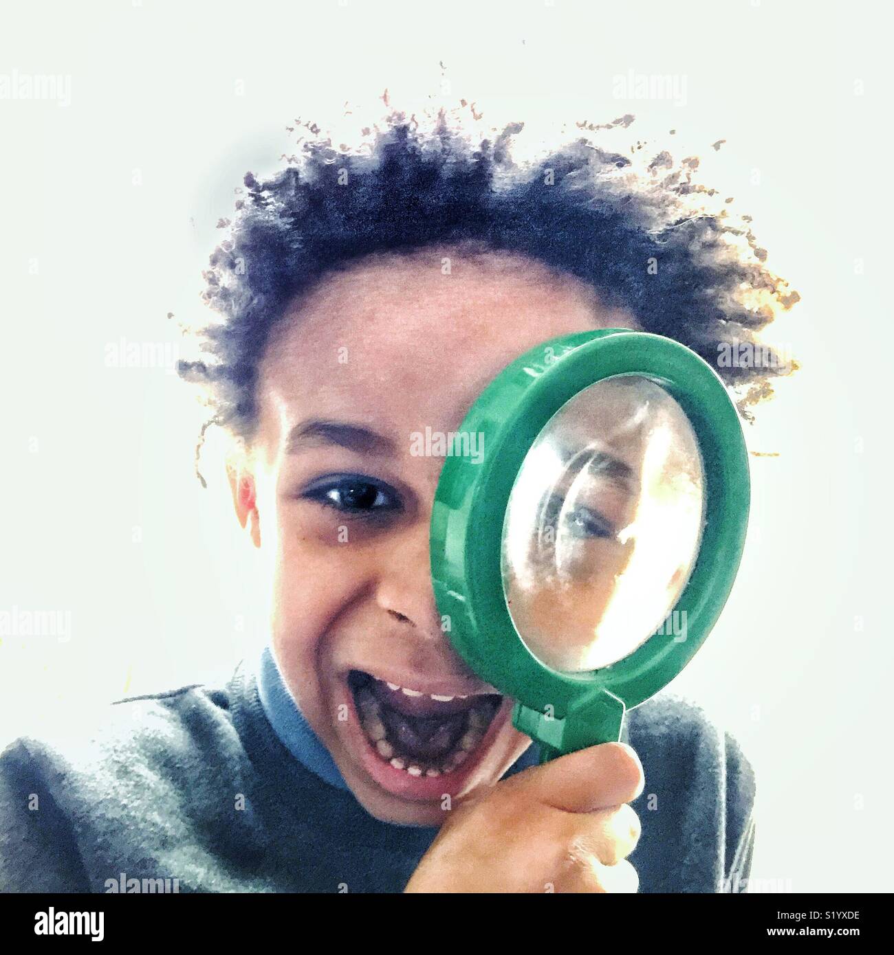 Little boy looks through a magnifying glass. Stock Photo