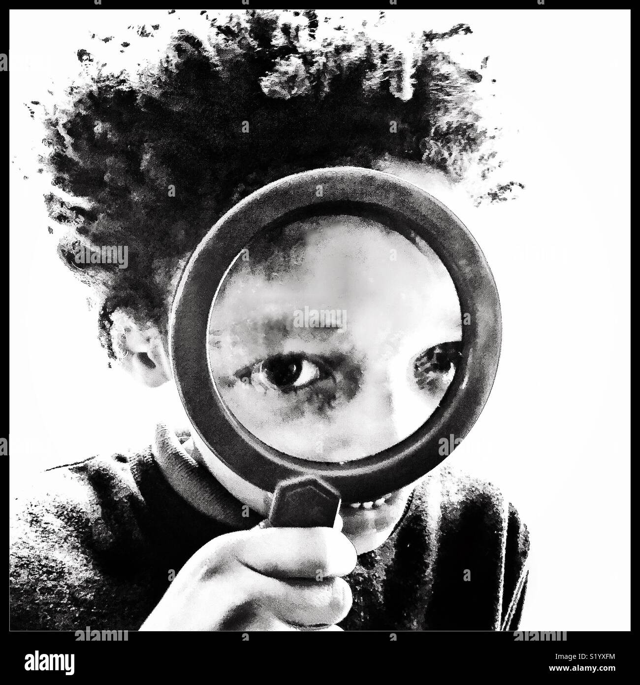 A little boy peers through a magnifying glass. Stock Photo