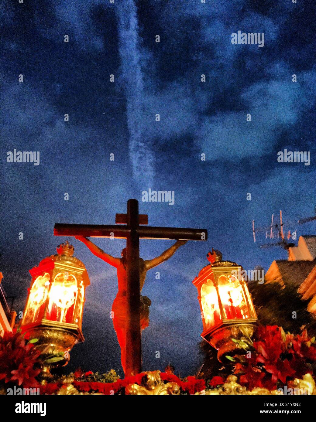 A chemtrail in the sky during a procesion of Jesus Christ crucified at easter holy week in Prado del Rey, Sierra de Cadiz, Andalusia, Spain Stock Photo
