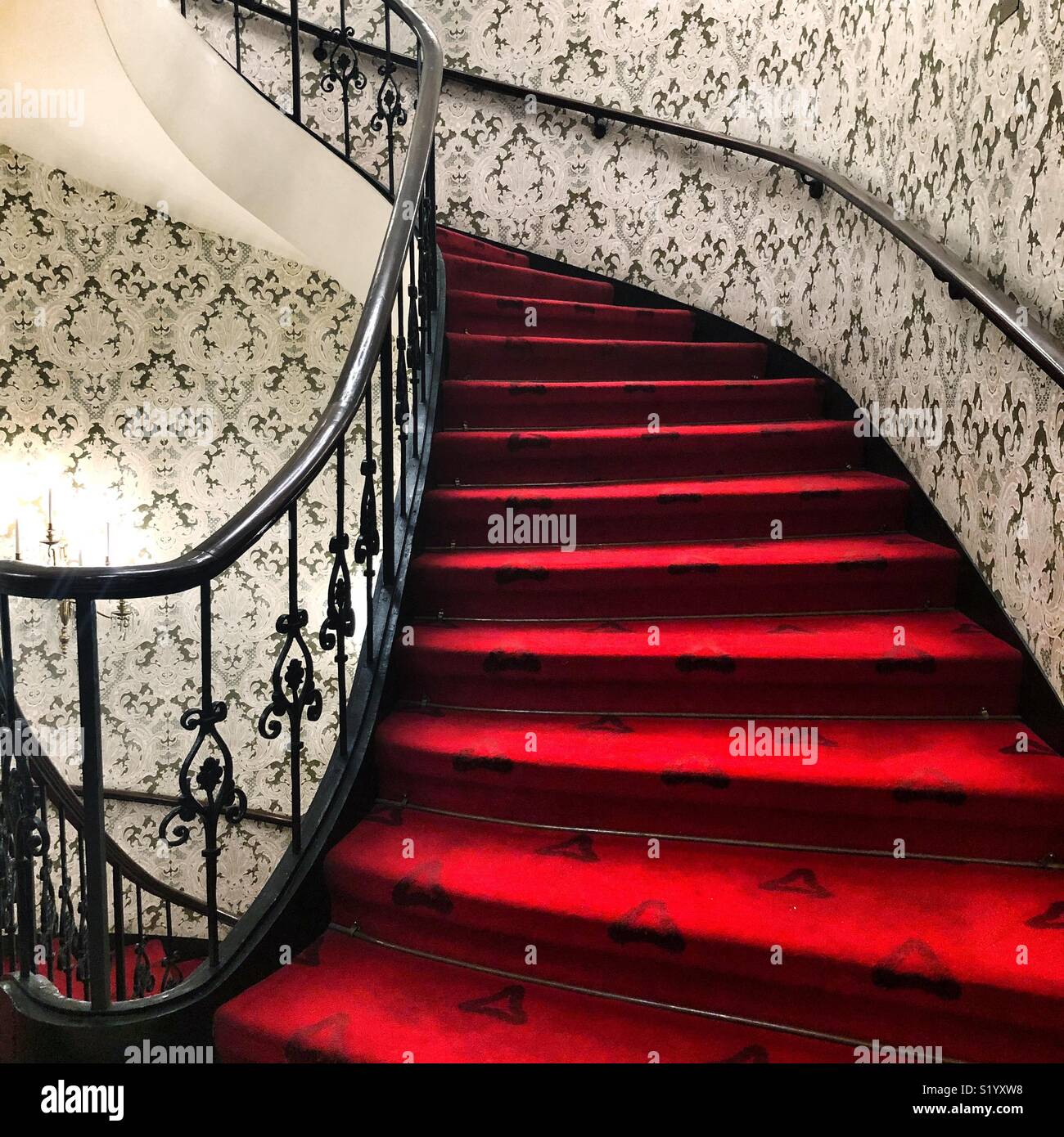 A winding red staircase with fancy black railings Stock Photo