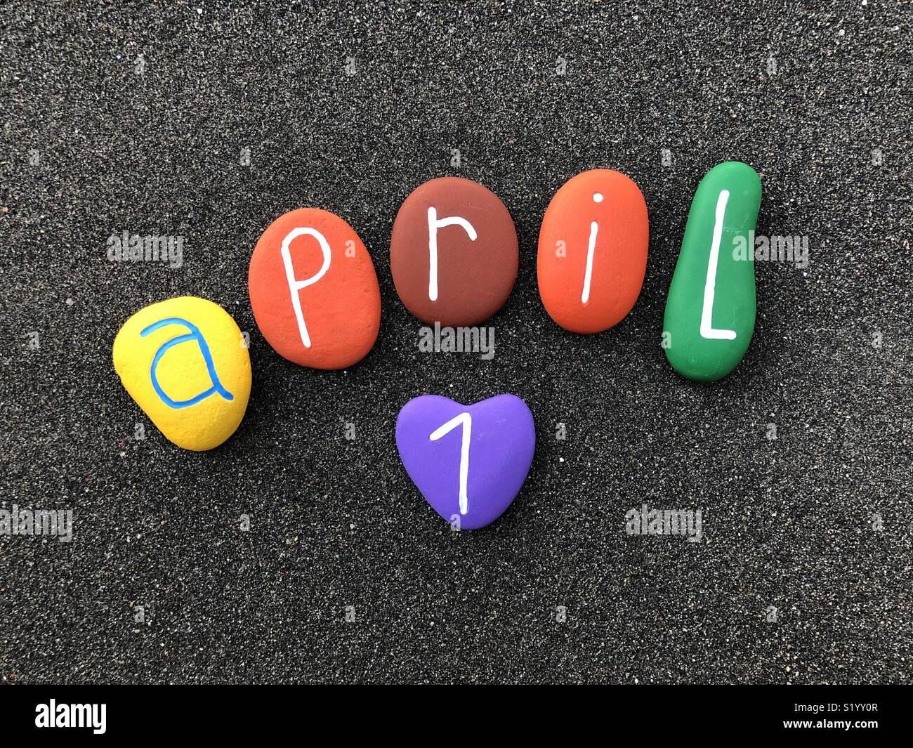 1 April, calendar date with multicolored stones over volcanic sand - Smartphone Captured Stock Image