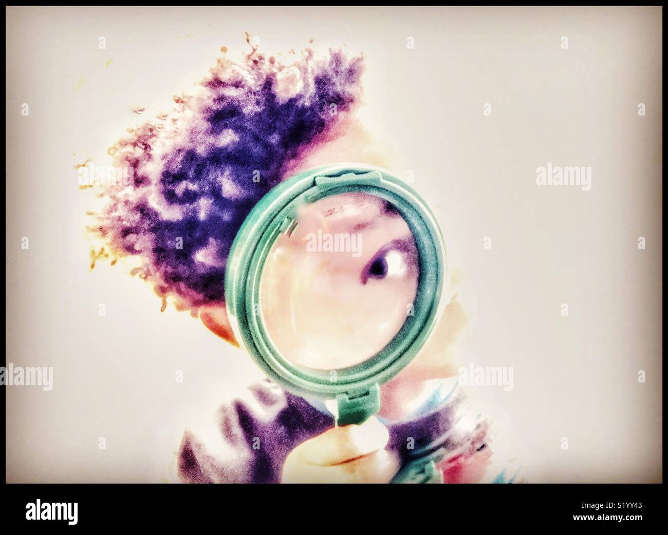 Child looking through a magnifying glass. Stock Photo