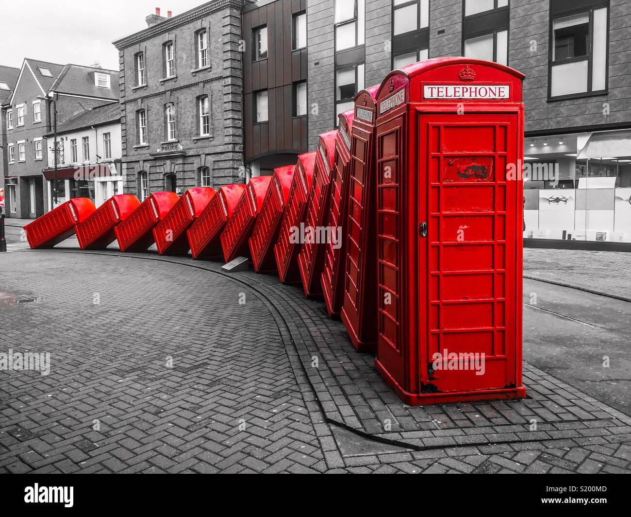 Red telephone boxes falling over in a dominoes effect Stock Photo