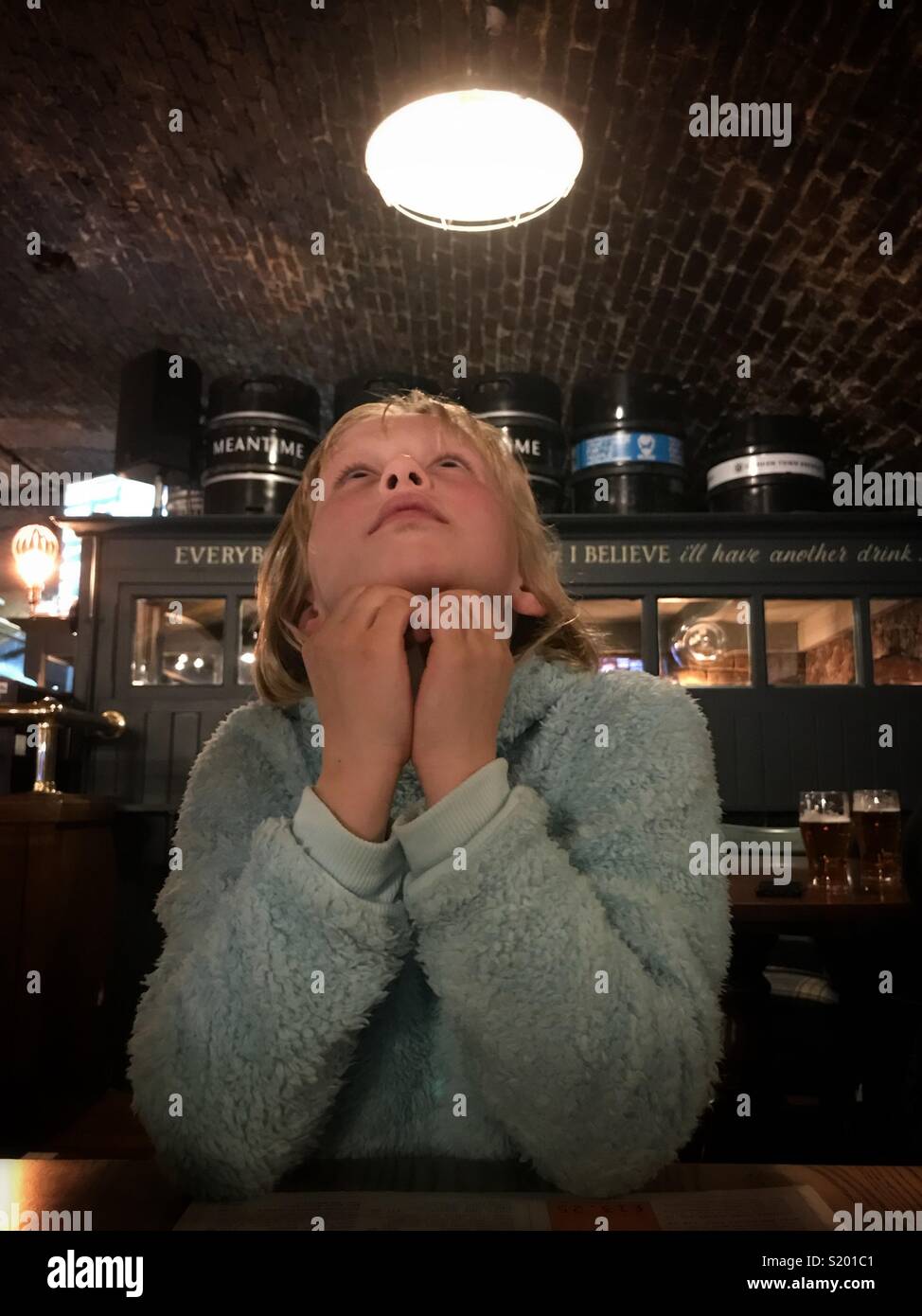 A girl looks upward as she hears a train passing overhead. - Smartphone Captured Stock Image
