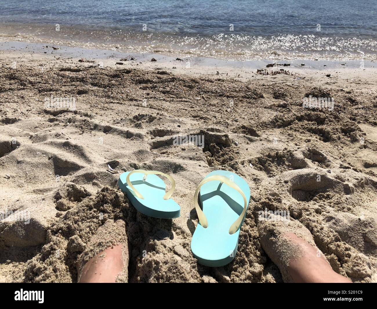 Feet and flip flops on a sandy beach - Smartphone Captured Stock Image