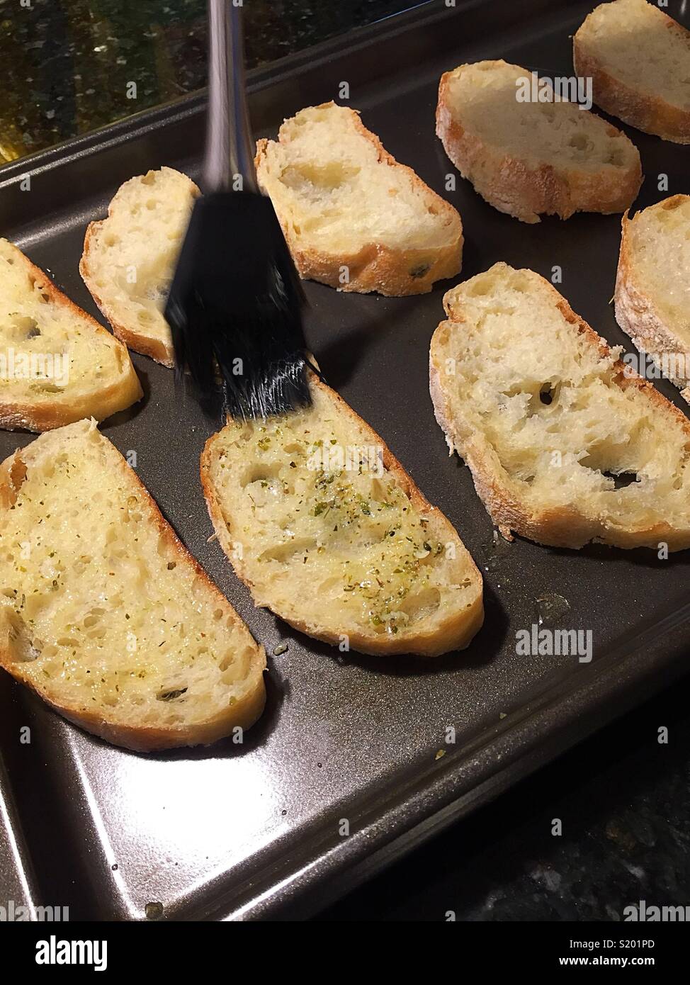 Homemade garlic bread being prepped with garlic butter, United States - Smartphone Captured Stock Image