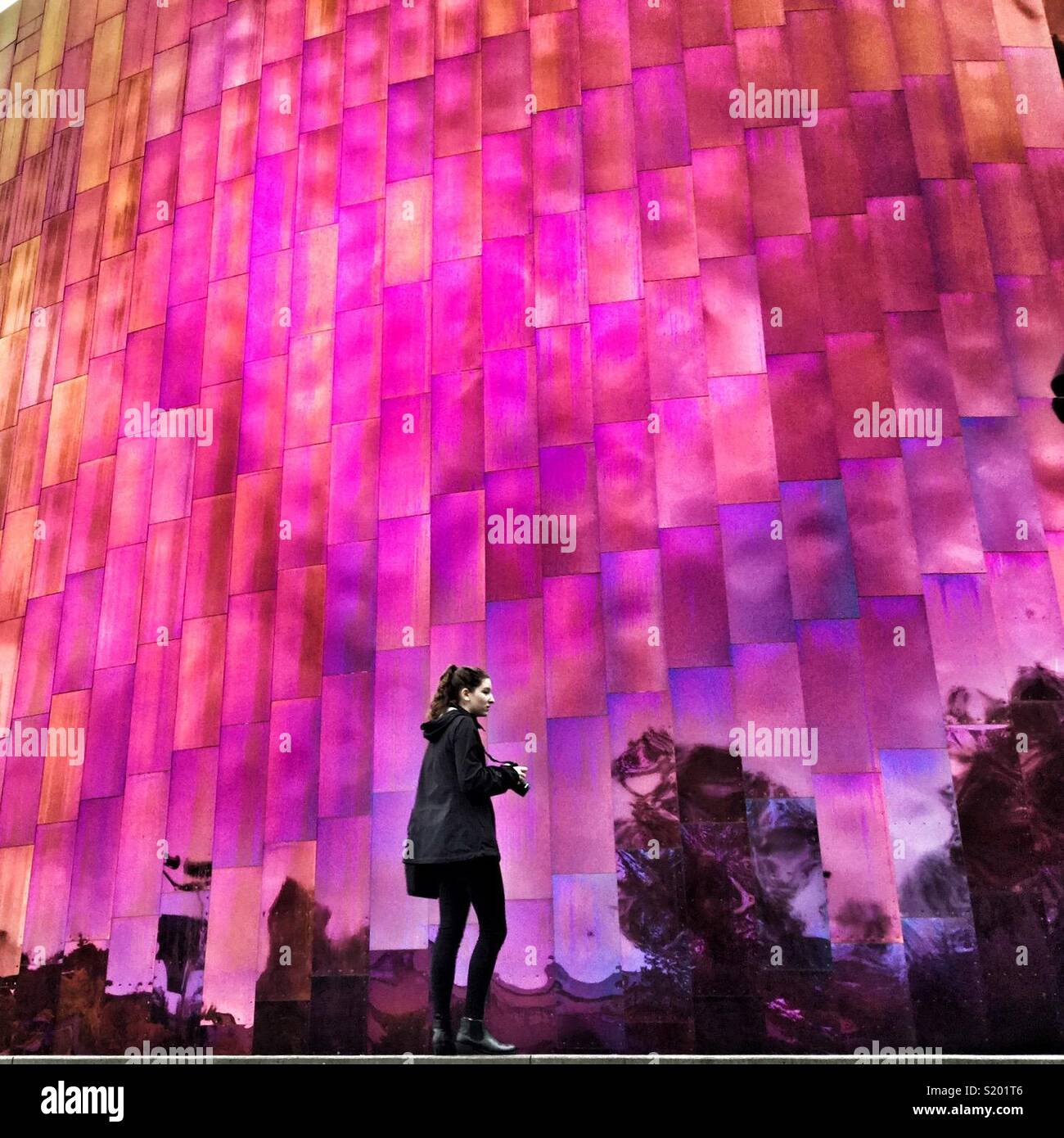 Young woman with camera at the Purple Rain wall of MoPop museum by architect Frank Gehry in Seattle - Smartphone Captured Stock Image