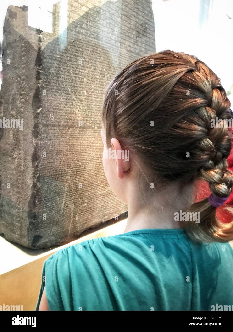 A girl examines the Rosetta Stone at the British Museum in London, England. - Smartphone Captured Stock Image