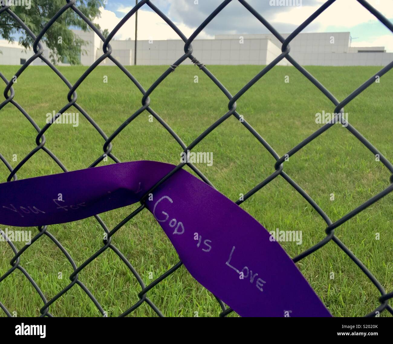 Tribute to Prince after his death in July 2016, a purple ribbon with the words 'God is Love' on a chain link fence, with Paisley Park, Prince's studio in the background. Stock Photo