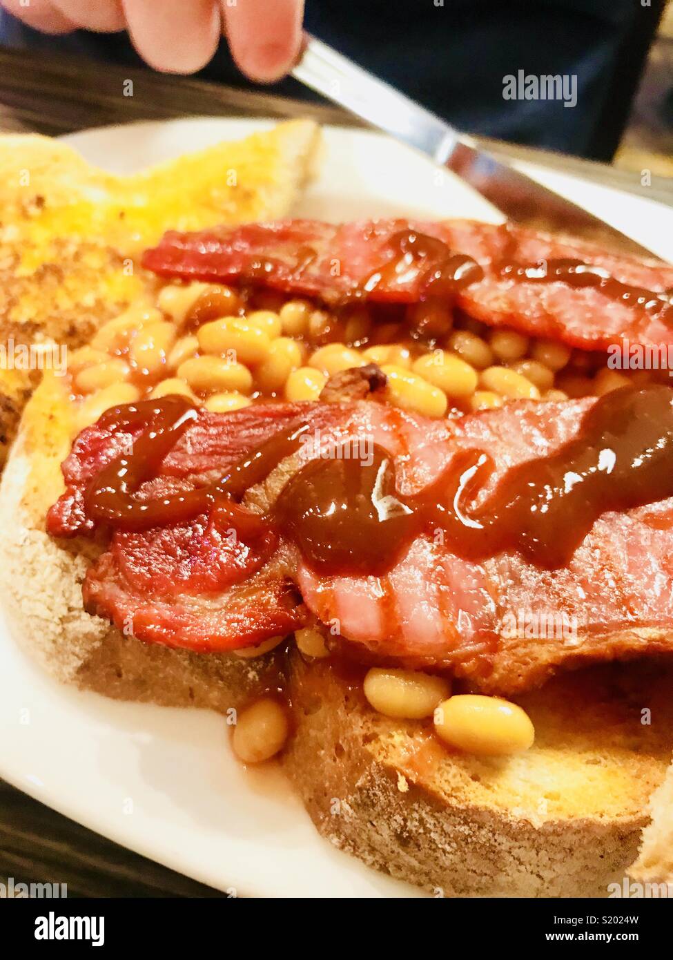 Baked beans on thick toast with bacon and brown sauce Stock Photo Alamy