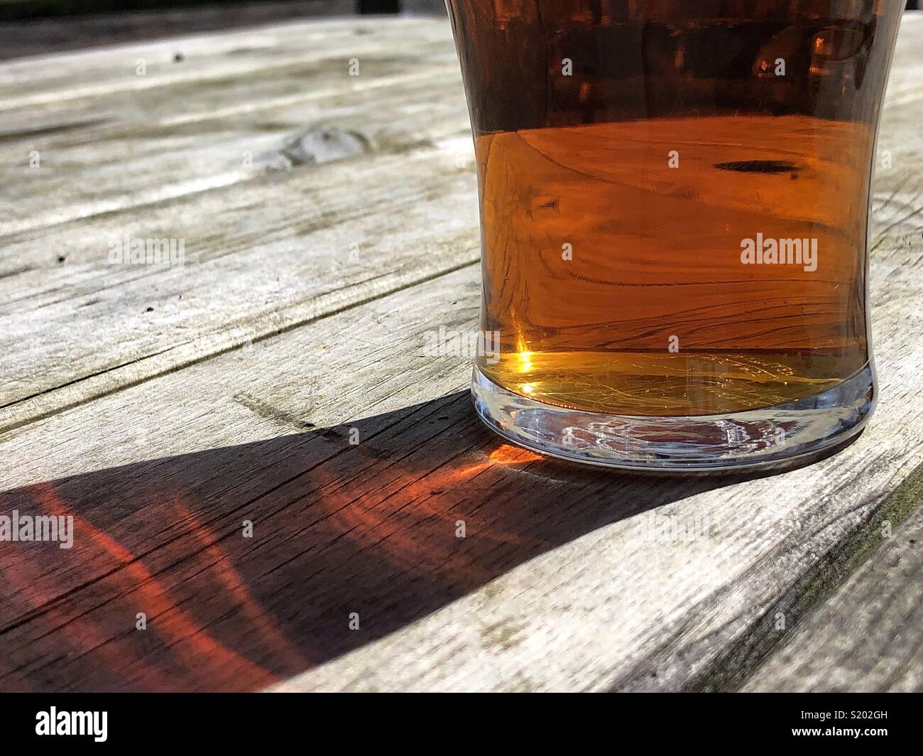 Pint of ale beer on a wooden pub bench on a summer day - Smartphone Captured Stock Image