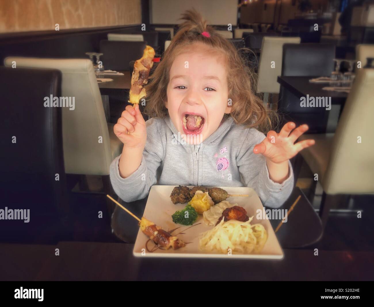 Happy little girl eating asian food in restaurant Paris France Stock Photo